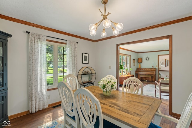 dining room with wood finished floors, a chandelier, baseboards, and crown molding