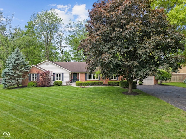 view of front facade with asphalt driveway, a front lawn, and brick siding