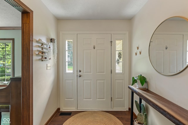 foyer with dark wood-style flooring, baseboards, and a textured ceiling