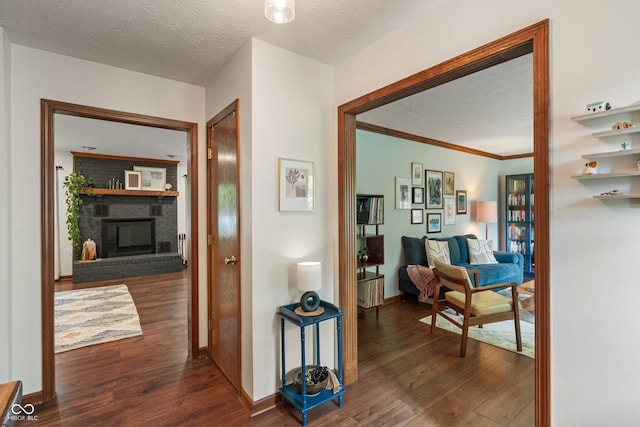 hall with wood finished floors, baseboards, a textured ceiling, and crown molding