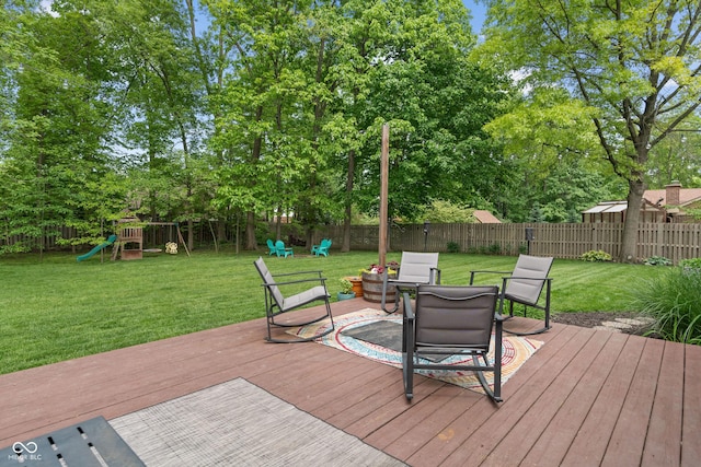 wooden deck with a playground, outdoor dining space, and view of wooded area