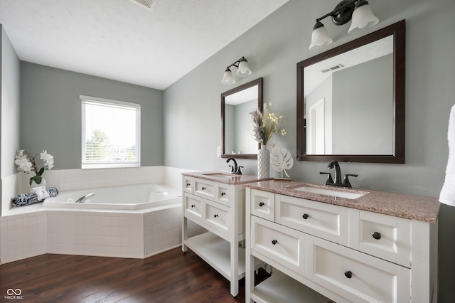 12331 Chiseled Stone Dr, Fishers, IN 46037 - bathroom with two vanities, wood finished floors, and a garden tub