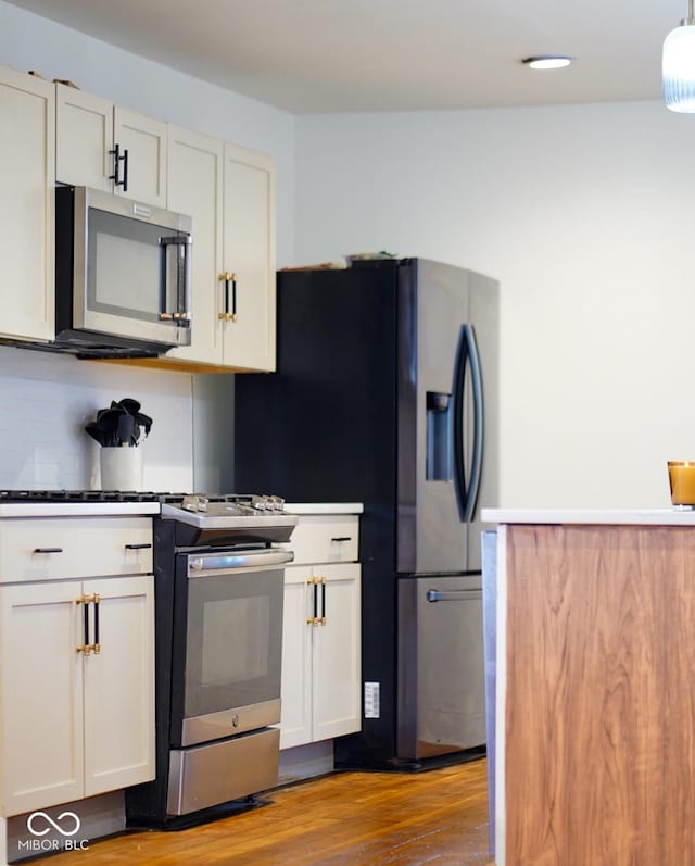 1730 Hoyt Ave, Indianapolis, IN 46203 - kitchen featuring stainless steel appliances, wood finished floors, white cabinetry, dark countertops, and tasteful backsplash