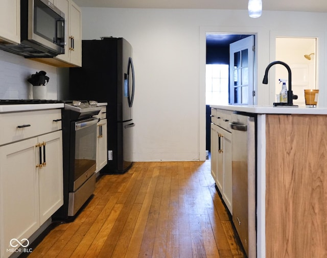 1730 Hoyt Ave, Indianapolis, IN 46203 - kitchen with appliances with stainless steel finishes, light wood-style floors, white cabinets, a sink, and light countertops