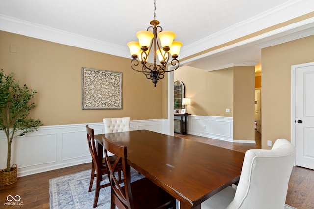 dining room with a chandelier, ornamental molding, wainscoting, wood finished floors, and a decorative wall