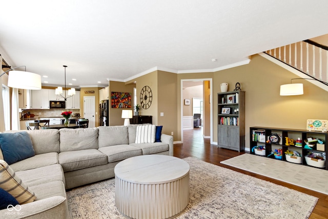 living room featuring wood finished floors, recessed lighting, baseboards, a chandelier, and ornamental molding