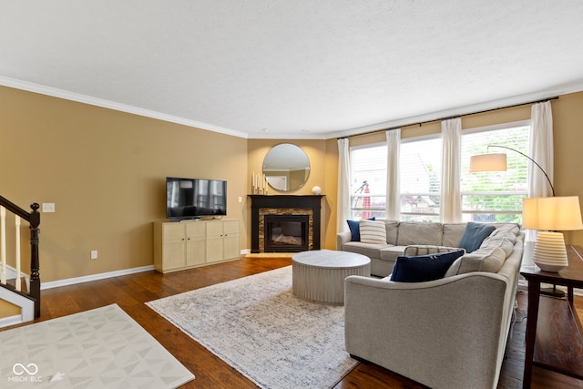 living area with a glass covered fireplace, stairway, dark wood finished floors, healthy amount of natural light, and crown molding
