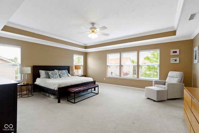 bedroom featuring a tray ceiling, ornamental molding, light carpet, ceiling fan, and baseboards
