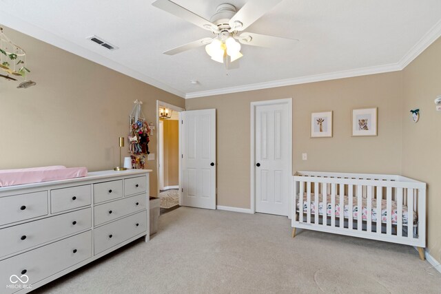 bedroom with crown molding, light carpet, baseboards, a crib, and a ceiling fan