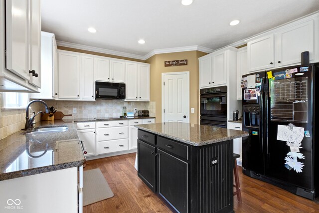 kitchen featuring black appliances, a sink, dark cabinetry, white cabinetry, and crown molding