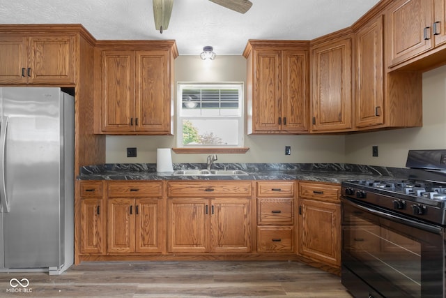 632 W Central Ave, Greensburg, IN 47240 - kitchen with freestanding refrigerator, black range with gas cooktop, a sink, and brown cabinetry
