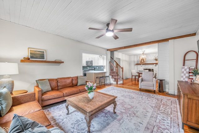 living area featuring ceiling fan, wood finished floors, stairway, and wooden ceiling