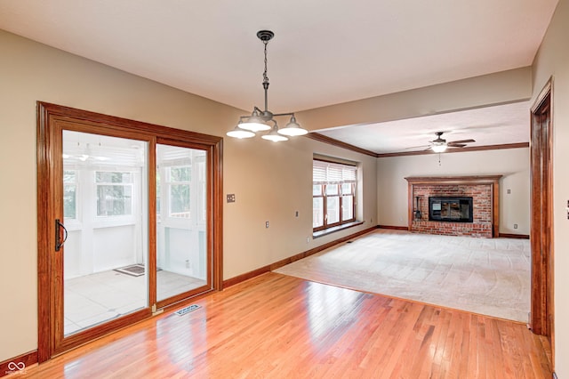 9158 Oak Knoll Ln, Fishers, IN 46037 - unfurnished living room featuring light wood-style flooring, a brick fireplace, a ceiling fan, and ornamental molding
