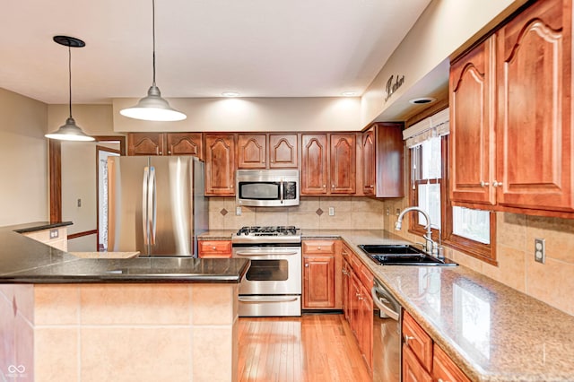 9158 Oak Knoll Ln, Fishers, IN 46037 - kitchen with stainless steel appliances, light wood finished floors, backsplash, decorative light fixtures, and stone counters