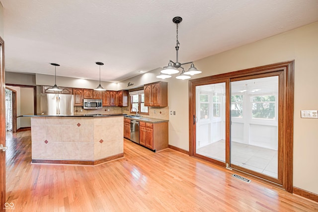 9158 Oak Knoll Ln, Fishers, IN 46037 - kitchen featuring appliances with stainless steel finishes, light wood finished floors, decorative light fixtures, and backsplash