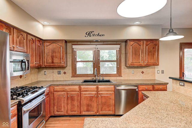 9158 Oak Knoll Ln, Fishers, IN 46037 - kitchen with appliances with stainless steel finishes, brown cabinets, light wood finished floors, decorative backsplash, and pendant lighting