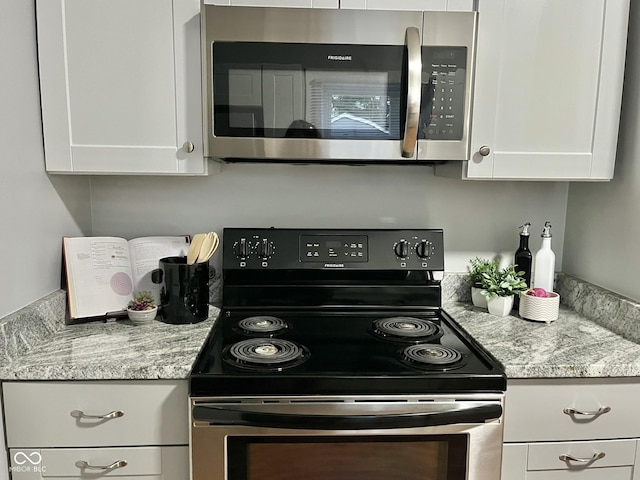 1661 S Talbott St, Indianapolis, IN 46225 - kitchen with range with electric cooktop, stainless steel microwave, white cabinetry, and light stone counters