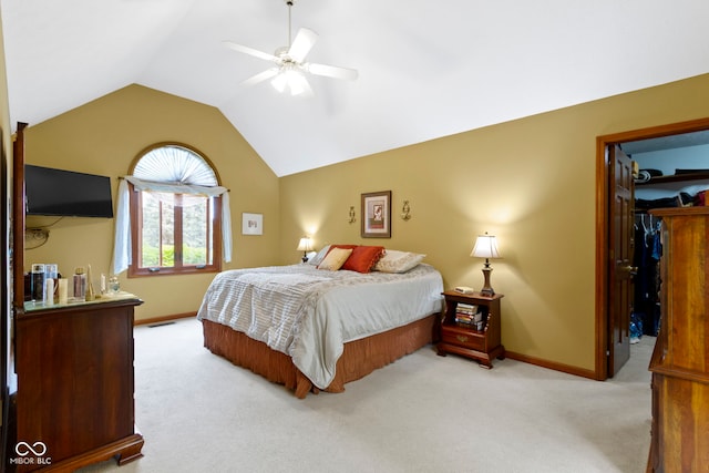 carpeted bedroom with vaulted ceiling, baseboards, a walk in closet, and ceiling fan