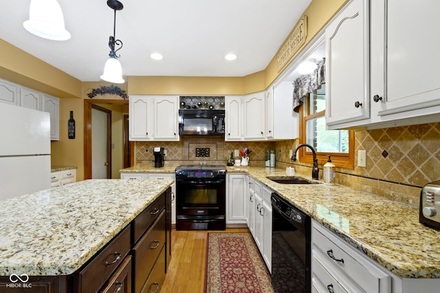kitchen with black appliances, a sink, light wood finished floors, white cabinets, and recessed lighting