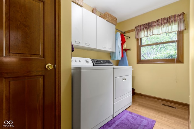 washroom featuring separate washer and dryer, light wood-type flooring, cabinet space, and baseboards