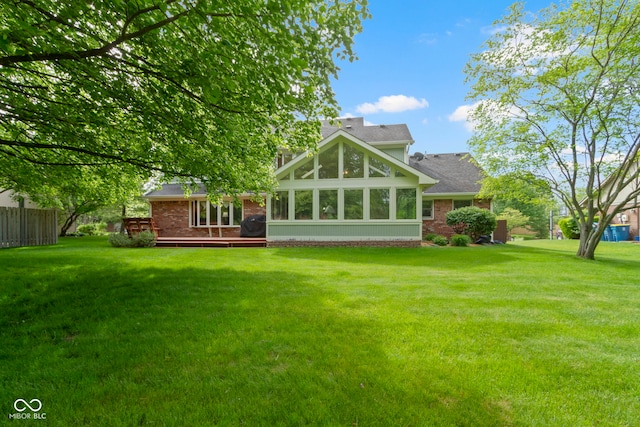 back of property featuring a deck, brick siding, and a sunroom