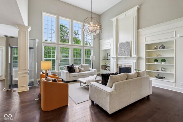 3744 Abney Point Dr, Carmel, IN 46077 - living room with a high ceiling, decorative columns, a tiled fireplace, built in features, and dark wood-type flooring