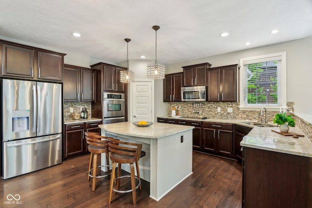3744 Abney Point Dr, Carmel, IN 46077 - kitchen with appliances with stainless steel finishes, a sink, dark brown cabinets, a center island, and light stone counters