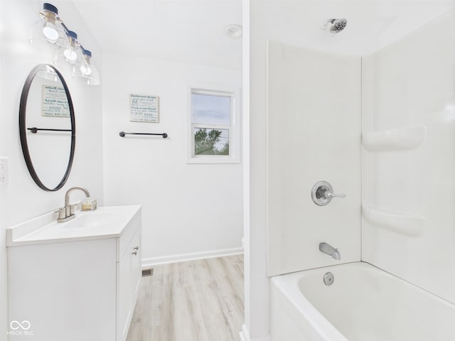 bathroom with wood finished floors, vanity, baseboards, and tub / shower combination