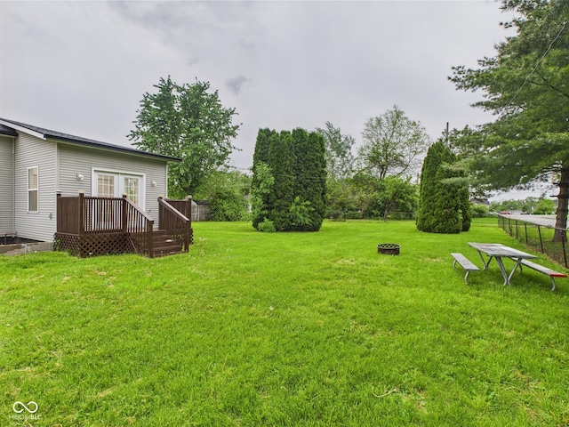 view of grassy yard with a deck, french doors, and an outdoor fire pit