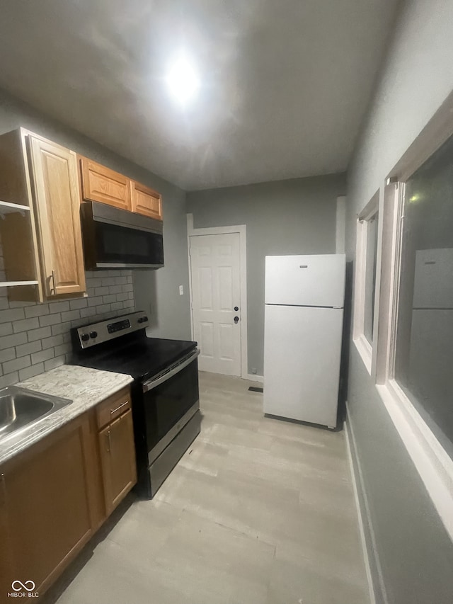 2116 Prospect St, Indianapolis, IN 46203 - kitchen with freestanding refrigerator, stainless steel range with electric cooktop, tasteful backsplash, light countertops, and a sink