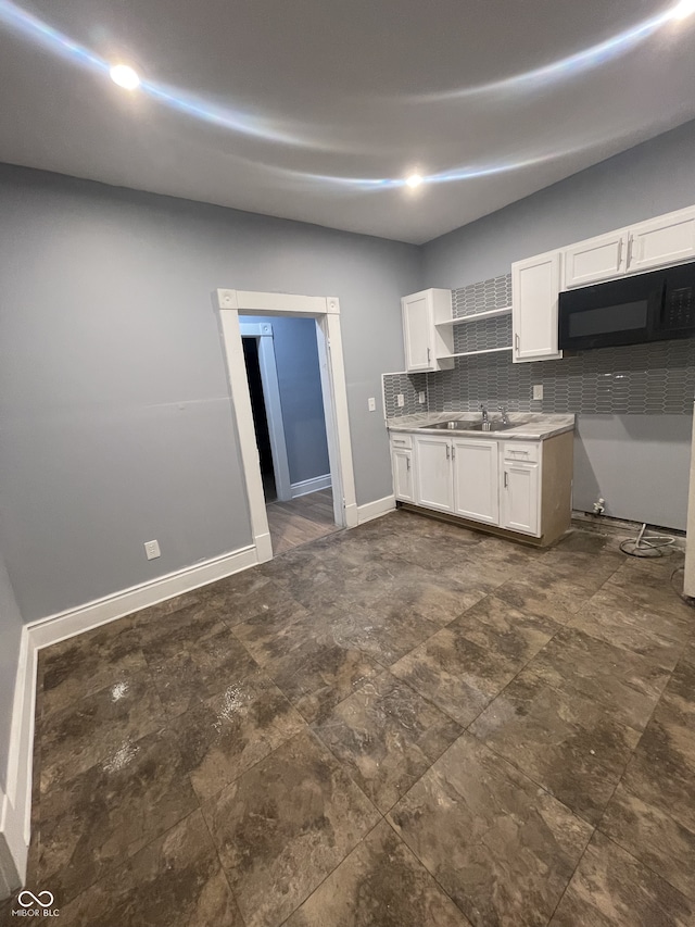 2116 Prospect St, Indianapolis, IN 46203 - kitchen featuring black microwave, white cabinets, baseboards, backsplash, and light countertops