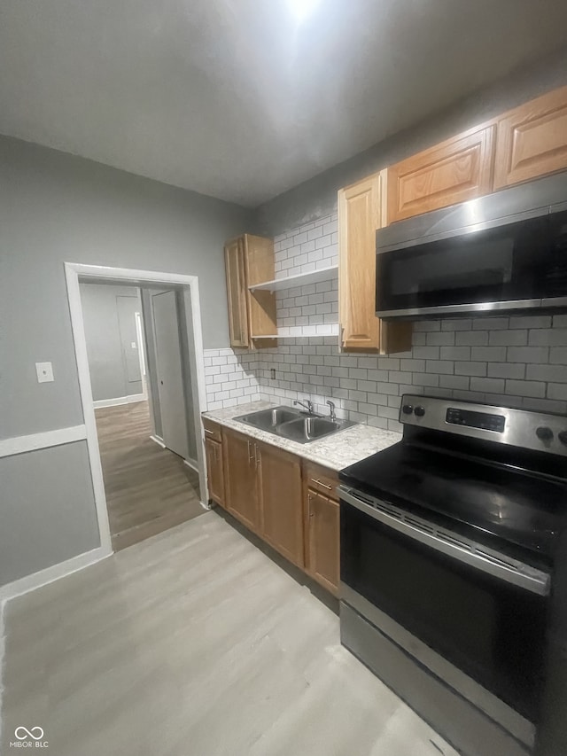 2116 Prospect St, Indianapolis, IN 46203 - kitchen with appliances with stainless steel finishes, a sink, light wood-style flooring, backsplash, and light countertops