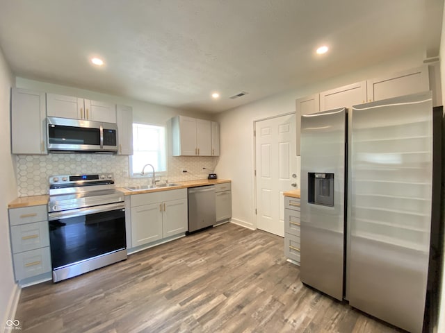 6150 E 25th St, Indianapolis, IN 46219 - kitchen featuring stainless steel appliances, a sink, backsplash, butcher block counters, and recessed lighting