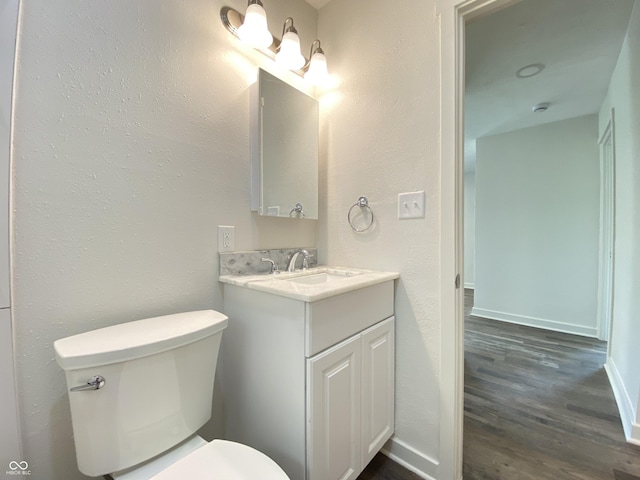 6150 E 25th St, Indianapolis, IN 46219 - bathroom with wood finished floors, toilet, vanity, baseboards, and a textured wall