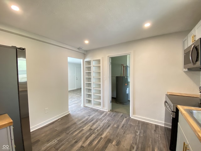 6150 E 25th St, Indianapolis, IN 46219 - kitchen featuring appliances with stainless steel finishes, electric water heater, dark wood-type flooring, built in shelves, and recessed lighting