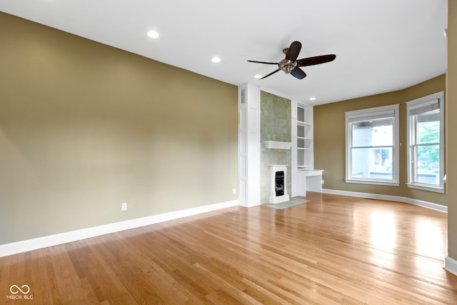 1526 Carrollton Ave, Indianapolis, IN 46202 - unfurnished living room with built in shelves, light wood-style flooring, a fireplace, baseboards, and a ceiling fan