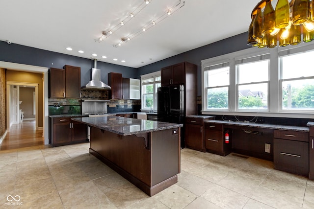 1526 Carrollton Ave, Indianapolis, IN 46202 - kitchen featuring wall chimney exhaust hood, decorative backsplash, a center island, dark stone countertops, and a kitchen breakfast bar