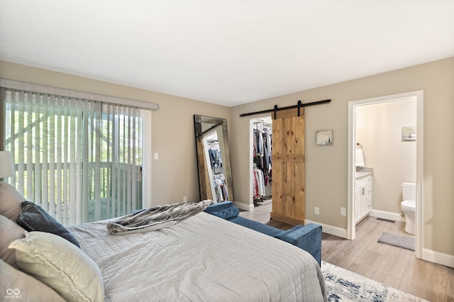 35 Osage Ct, Columbus, IN 47201 - bedroom featuring a barn door, light wood finished floors, a spacious closet, baseboards, and ensuite bathroom