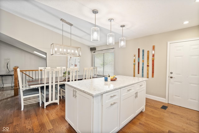 35 Osage Ct, Columbus, IN 47201 - kitchen featuring light wood finished floors, white cabinetry, hanging light fixtures, light stone counters, and vaulted ceiling