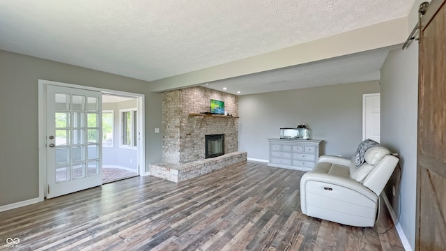 80 E College Ave, Martinsville, IN 46151 - living area with wood finished floors, baseboards, a textured ceiling, a brick fireplace, and a barn door