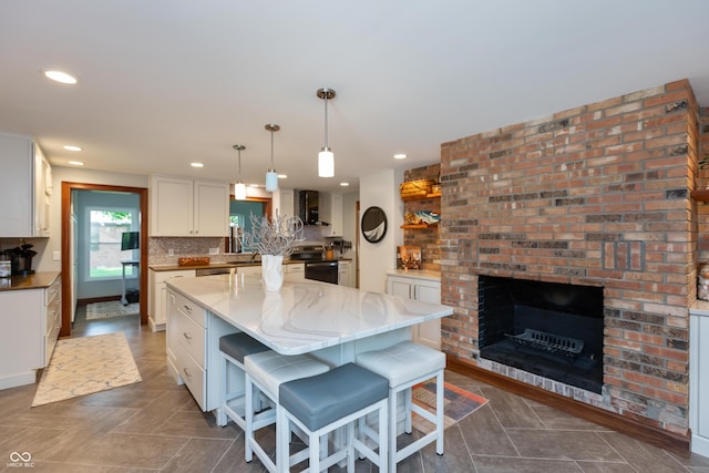 1541 Stadium Dr, Seymour, IN 47274 - kitchen with recessed lighting, wall chimney range hood, white cabinets, a kitchen island, and a breakfast bar area