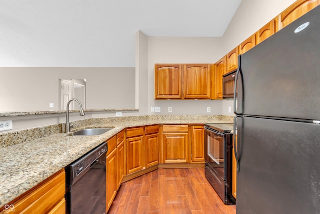 1139 Fernwood Way, Plainfield, IN 46168 - kitchen featuring black appliances, a sink, light stone countertops, wood finished floors, and brown cabinetry