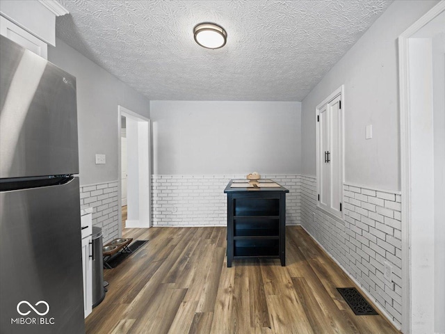 547 W Taylor St, Shelbyville, IN 46176 - kitchen with freestanding refrigerator, wainscoting, dark wood finished floors, a textured ceiling, and brick wall