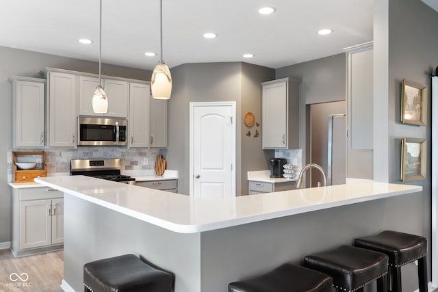 4659 W Otway Ln, New Palestine, IN 46163 - kitchen with appliances with stainless steel finishes, a breakfast bar, a peninsula, light wood-type flooring, and recessed lighting