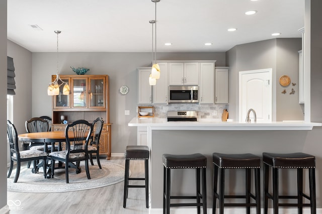 4659 W Otway Ln, New Palestine, IN 46163 - kitchen with appliances with stainless steel finishes, light wood-style floors, a breakfast bar, a sink, and backsplash