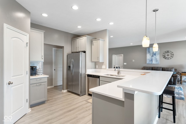4659 W Otway Ln, New Palestine, IN 46163 - kitchen with appliances with stainless steel finishes, a sink, a peninsula, light wood-style flooring, and light countertops