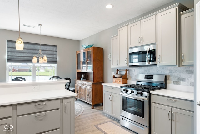 4659 W Otway Ln, New Palestine, IN 46163 - kitchen featuring appliances with stainless steel finishes, decorative backsplash, light countertops, light wood-type flooring, and decorative light fixtures