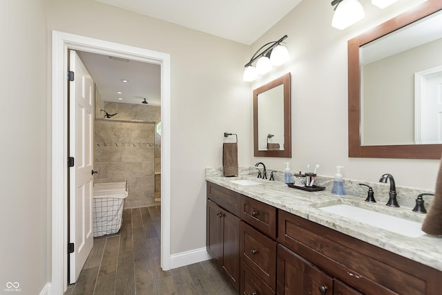 7430 Franklin Parke Woods, Indianapolis, IN 46259 - bathroom with double vanity, a tile shower, wood finished floors, and baseboards
