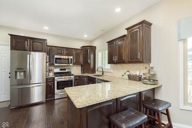 7430 Franklin Parke Woods, Indianapolis, IN 46259 - kitchen with appliances with stainless steel finishes, a sink, a peninsula, dark brown cabinets, and decorative backsplash