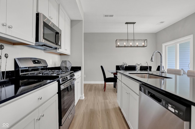 6683 Halsey St, Zionsville, IN 46077 - kitchen featuring stainless steel appliances, a sink, a chandelier, light wood-type flooring, and dark countertops